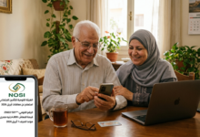 زوجان مسنان مبتسمان في المنزل يتحققان من تفاصيل صرف معاش شهر أبريل 2026 عبر تطبيق هاتف ذكي يعرض شعار الهيئة القومية للتأمين الاجتماعي المصرية.