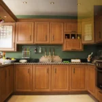 لقطة قريبة تظهر نظام أبواب منزلقة خشبية (Pocket Doors) في منتصف الحركة، تكشف عن مطبخ مخفي مودرن 2026 يتميز بسطح رخامي أبيض فاخر، أجهزة مدمجة بذكاء، وإضاءة LED ناعمة داخل جدار انسيابي.