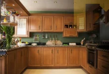 لقطة قريبة تظهر نظام أبواب منزلقة خشبية (Pocket Doors) في منتصف الحركة، تكشف عن مطبخ مخفي مودرن 2026 يتميز بسطح رخامي أبيض فاخر، أجهزة مدمجة بذكاء، وإضاءة LED ناعمة داخل جدار انسيابي.