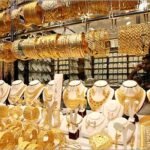 عرض حي لسبائك ذهبية وعملات معدنية مع شاشة بورصة توضح أسعار الذهب فى مصر اليوم.