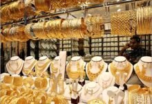 عرض حي لسبائك ذهبية وعملات معدنية مع شاشة بورصة توضح أسعار الذهب فى مصر اليوم.